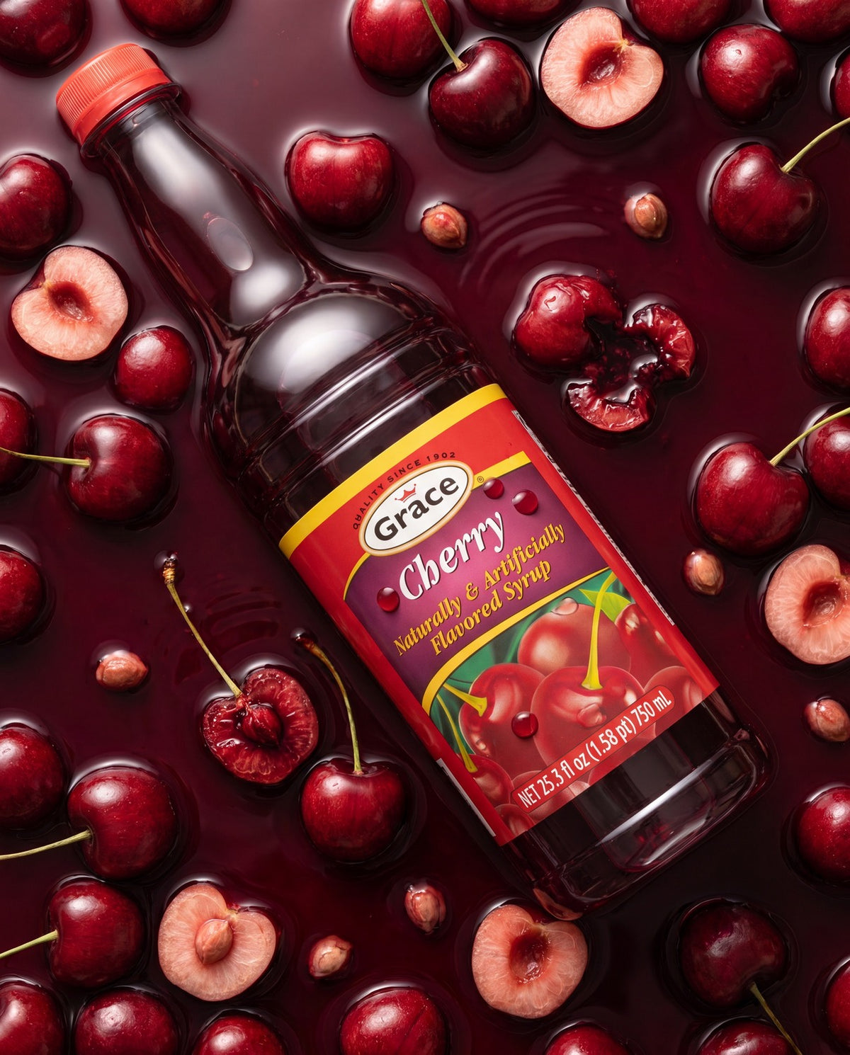 Angled view of Grace Cherry Syrup bottle showcasing its cherry flavor label surrounded by whole and halved cherries