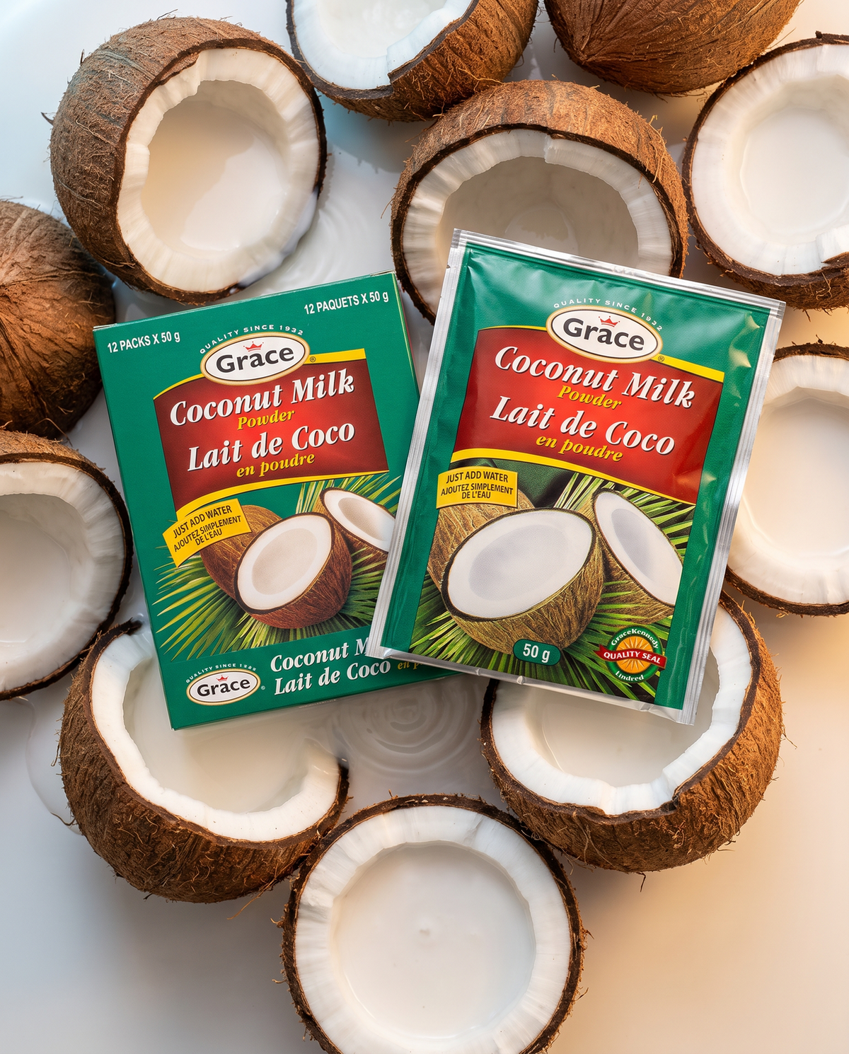 Top view of Grace Coconut Milk Powder box and sachet showcasing 50 g packets with coconut halves background