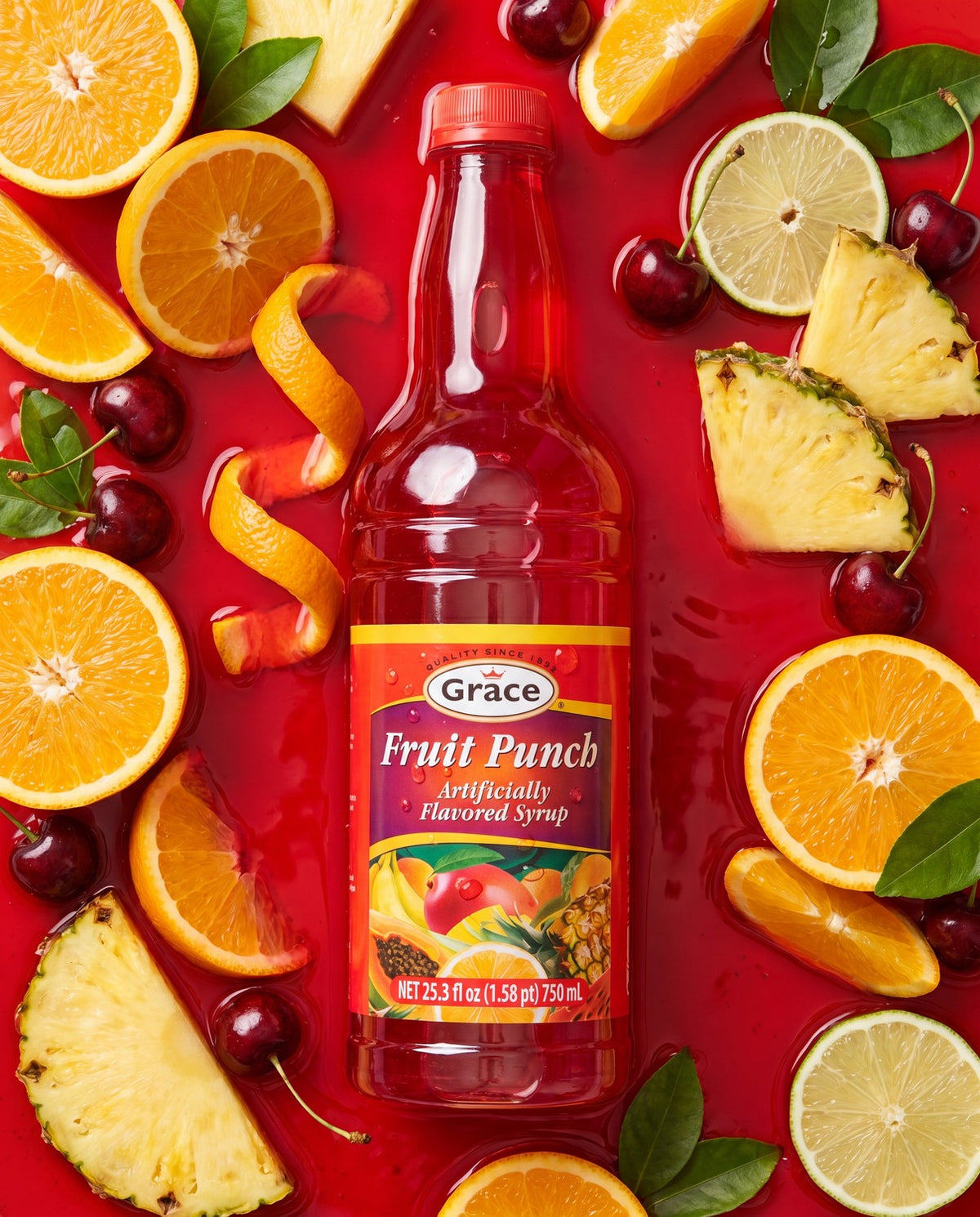 Front view of Grace Fruit Punch Syrup bottle showcasing red syrup with citrus, cherries, and pineapple on a red background