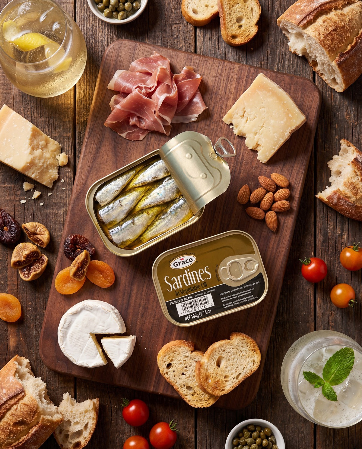 Overhead view of Grace Sardines in Vegetable Oil showcasing an open tin of sardines with bread and cheese on a wooden table