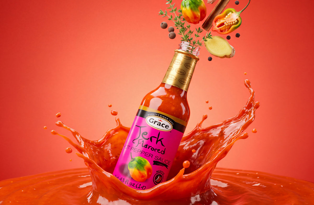 Angled view of Grace Jerk Flavored Hot Pepper Sauce showcasing a dramatic sauce splash against a red background