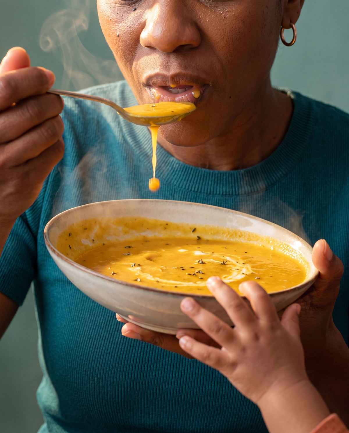Woman tasting steaming soup from a bowl