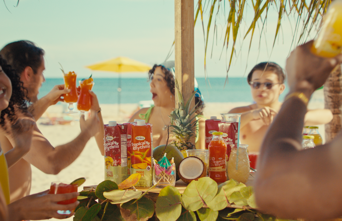 Friends toasting tropical drinks at a beachside gathering with Tropical Rhythms beverages