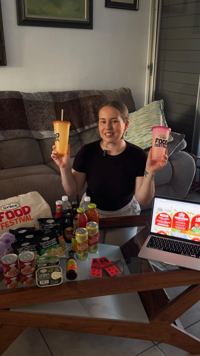 Woman holding two Food Festival cups while showing Grace products displayed on a coffee table in a living room