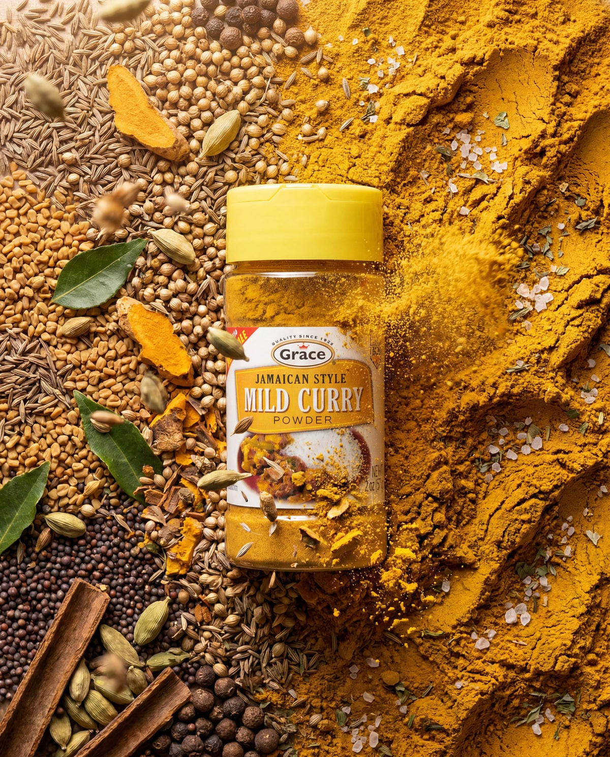 Front view of Grace Jamaican Style Mild Curry Powder, 2 ounce jar with yellow lid surrounded by whole spices and curry powder