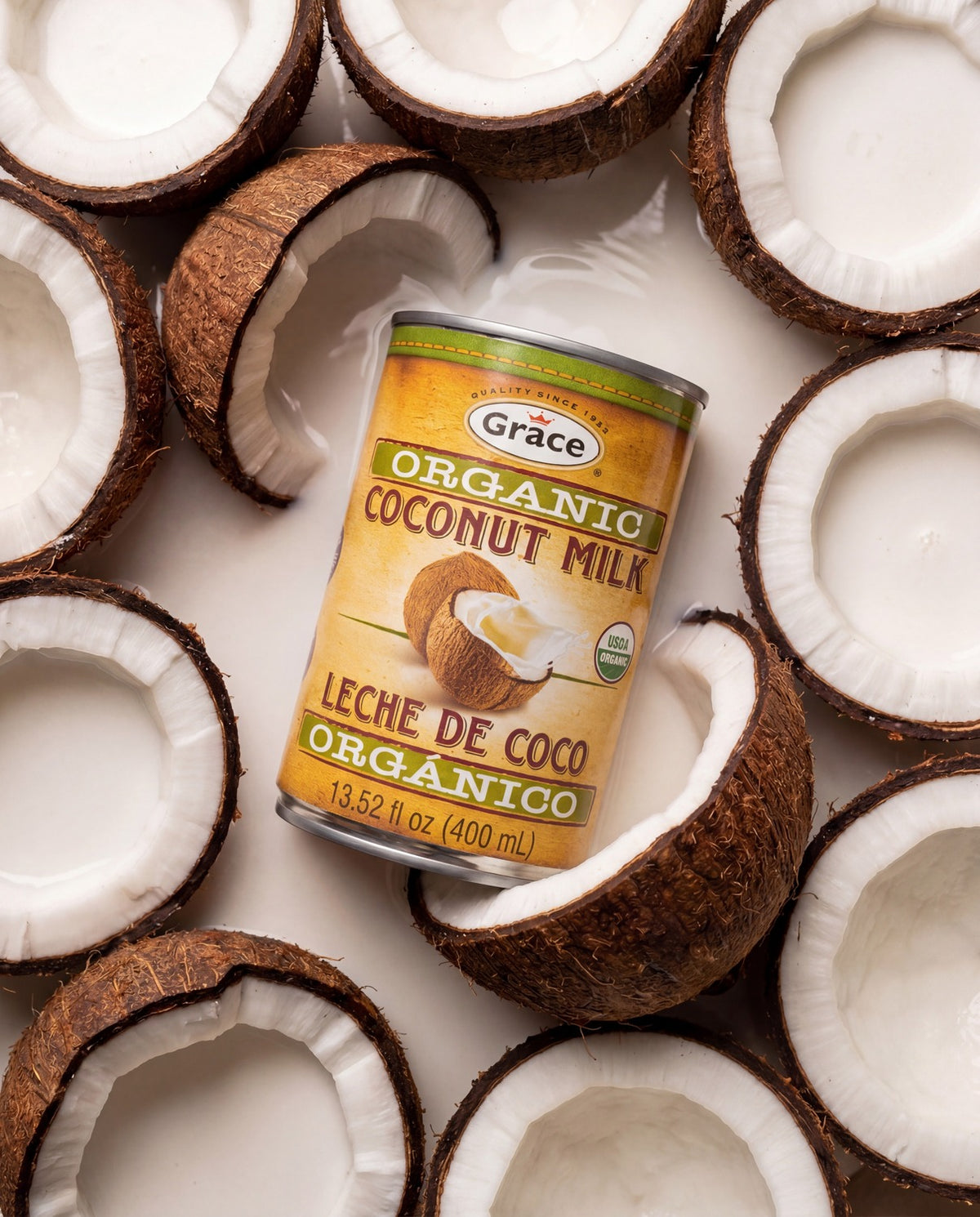 Angled view of Grace Organic Coconut Milk showcasing organic labeling and 400 ml size with halved coconuts on a white background
